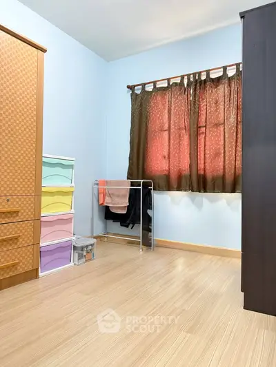 Cozy bedroom with wooden flooring, wardrobe, and colorful storage drawers.