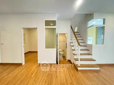 Spacious modern interior with wooden flooring and staircase, perfect for stylish living.