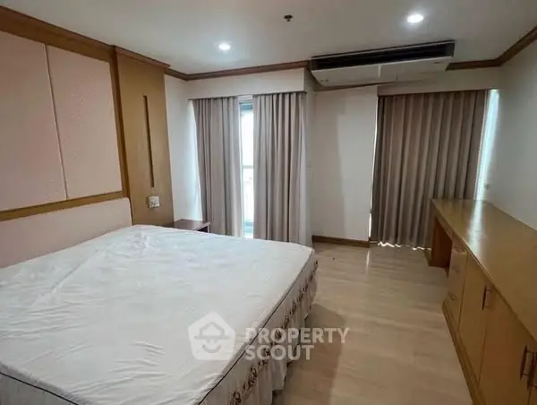 Spacious bedroom with large windows and modern air conditioning unit.