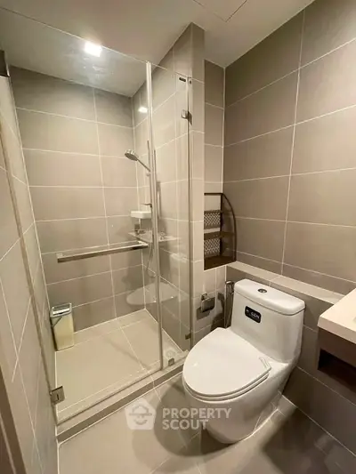 Modern bathroom with glass shower and sleek fixtures in contemporary apartment.