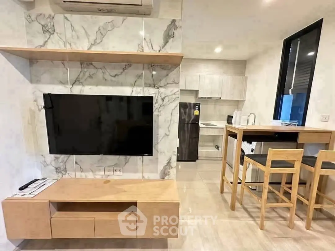 Modern living room with marble accent wall and sleek kitchen area.