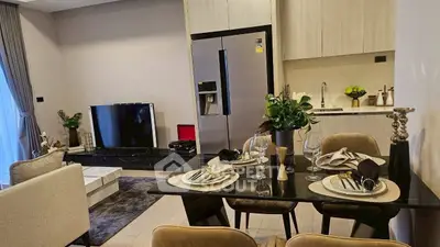 Modern open-plan living room and kitchen with elegant dining setup and sleek appliances.