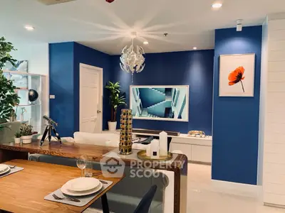 Modern living room with stylish decor and blue accent wall, featuring a sleek TV setup and elegant dining area.