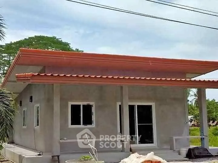 Modern single-story house with flat roof and spacious porch in a serene neighborhood.