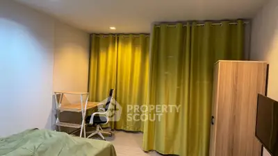 Cozy bedroom with study desk and green curtains, perfect for relaxation and productivity.