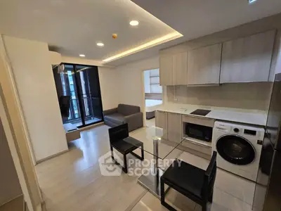 Modern open-plan living room with kitchen, featuring sleek furniture and appliances, ideal for urban living.