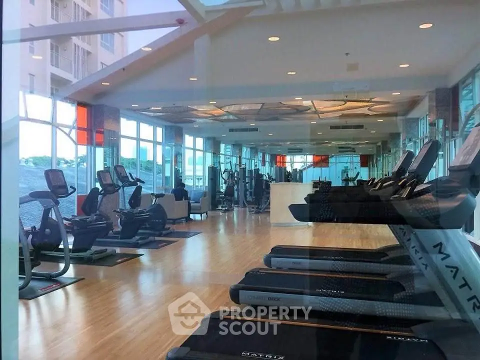 Spacious modern gym with state-of-the-art equipment and panoramic windows in luxury residential building.