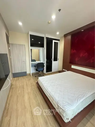 Modern bedroom with wooden flooring, stylish wardrobe, and cozy workspace.