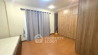 Spacious bedroom with wooden flooring and large wardrobe, perfect for comfortable living.