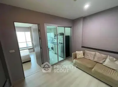 Modern apartment interior with cozy living room and adjacent kitchen featuring washing machine and fridge.