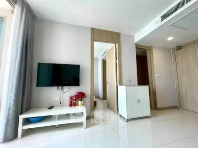 Modern living room with wall-mounted TV and sleek furniture in a bright apartment.