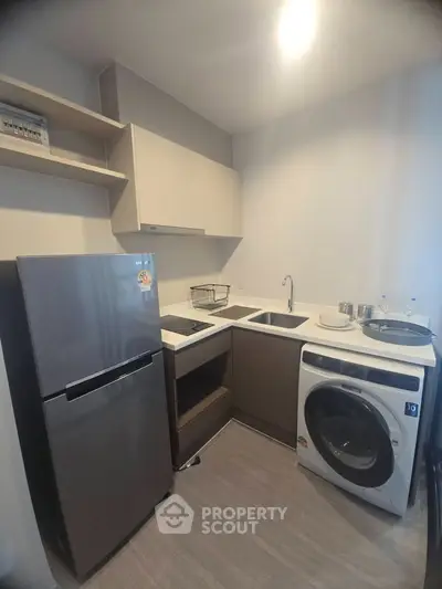 Modern kitchen with sleek appliances and efficient layout, featuring a fridge, washing machine, and ample storage.