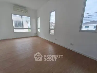 Spacious empty room with large windows and wooden flooring in modern home