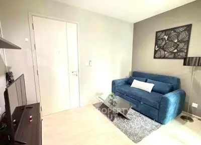 Modern living room with blue sofa, glass coffee table, and stylish decor