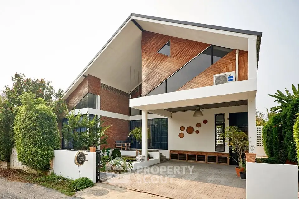 Modern architectural house with unique wooden facade and spacious driveway, surrounded by lush greenery.
