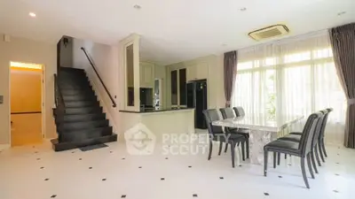 Spacious open-plan dining area with modern kitchen and elegant staircase