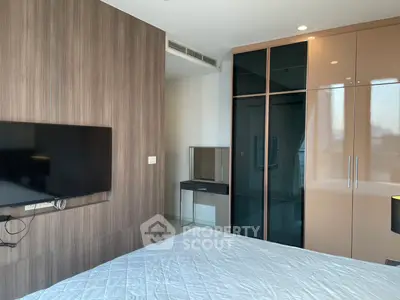 Modern bedroom with sleek wardrobe and wall-mounted TV in stylish apartment.