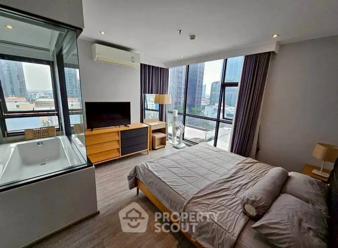 Luxurious bedroom with city view and in-room bathtub, modern decor and ample natural light.