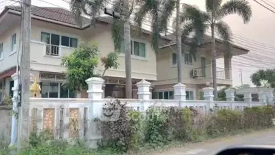 Charming two-story house with lush garden and palm trees, perfect for family living.