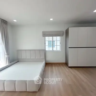 Spacious minimalist bedroom with modern design and ample natural light.