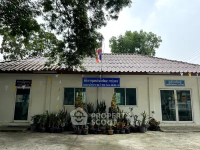 Charming single-story building with lush potted plants and a welcoming entrance, ideal for community or office use.