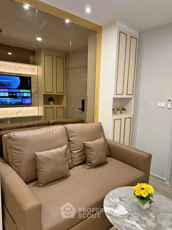 Modern living room with stylish brown sofa, mirrored wall, and elegant decor accents.