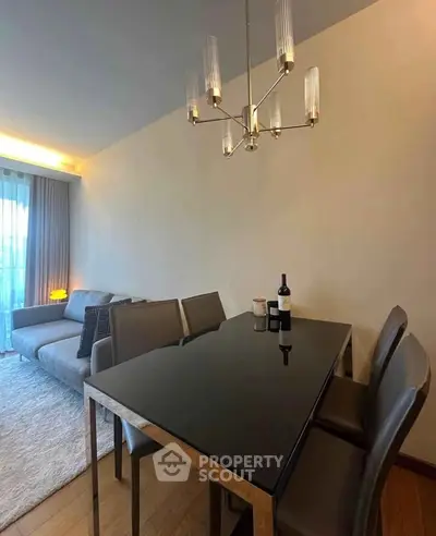 Modern living room with elegant dining area and stylish chandelier, featuring a cozy sofa and ambient lighting.