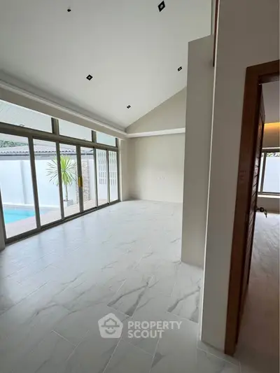 Spacious modern living room with pool view and elegant tile flooring.