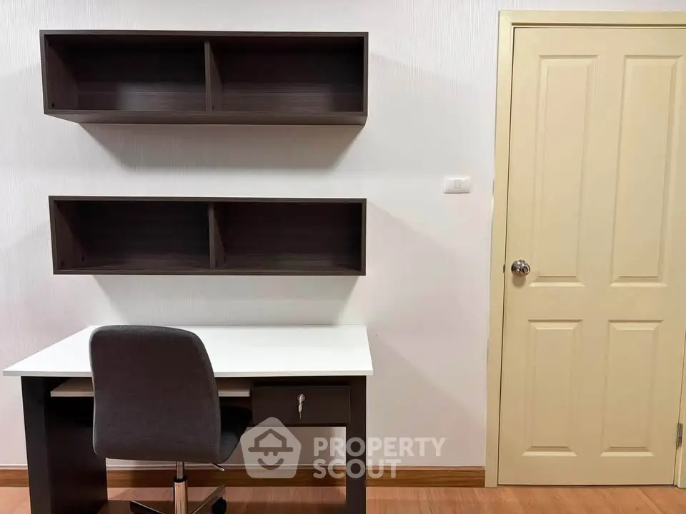 Modern study room with sleek desk, chair, and wall-mounted shelves, perfect for productivity.