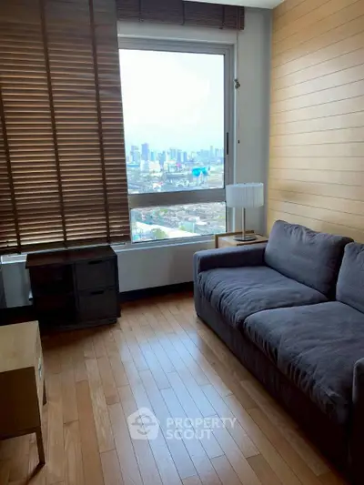 Modern living room with city view, wooden flooring, and cozy gray sofa.