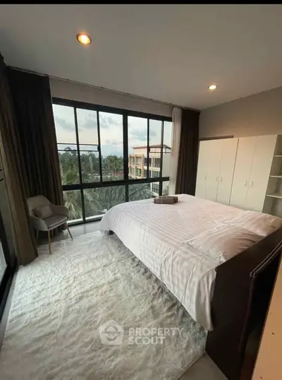Spacious bedroom with large windows offering a stunning view, featuring a cozy bed and modern decor.