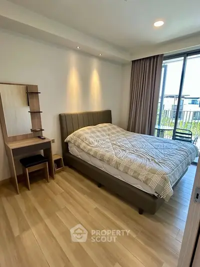 Modern bedroom with cozy bed and natural light from large window, featuring elegant wooden flooring.