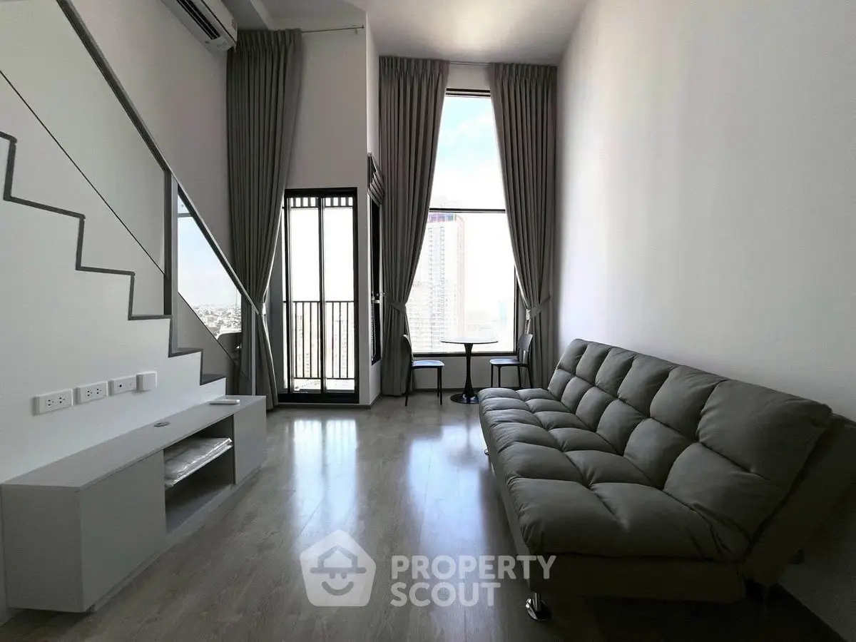 Modern living room with high ceiling and large windows offering city views