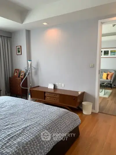 Spacious bedroom with modern decor and wooden flooring, featuring a cozy bed and stylish furniture.