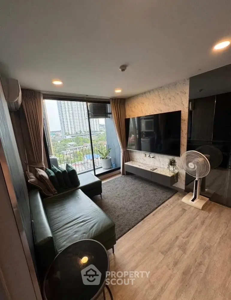 Modern living room with large TV and city view from balcony