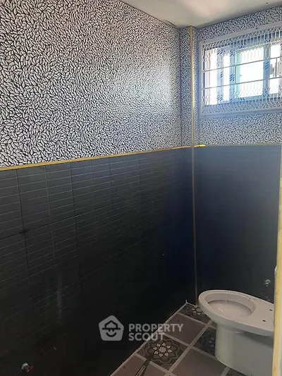 Modern bathroom with unique patterned tiles and window for natural light.