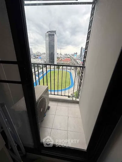 Compact balcony with city view overlooking a sports track, ideal for urban living.