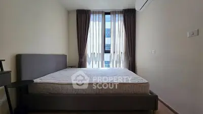 Spacious bedroom with large window and modern furnishings in a stylish apartment.