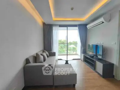 Modern living room with stylish sofa, TV, and balcony view in a contemporary apartment.