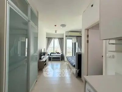 Modern studio apartment with open layout and city view, featuring sleek furniture and natural light.