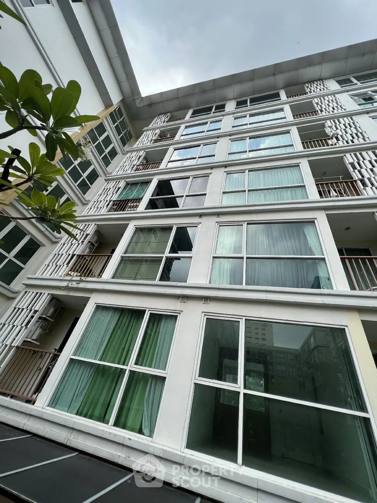 Modern multi-story apartment building with large windows and balconies, offering urban living in a vibrant community.