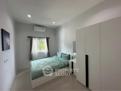 Modern bedroom with sleek design, featuring a comfortable bed, air conditioning, and ample natural light.