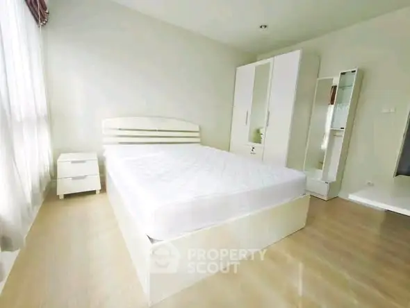 Bright and spacious bedroom with modern white furniture and natural light.
