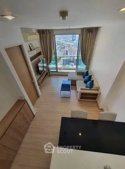 Modern living room with city view, featuring sleek furniture and large windows for natural light.