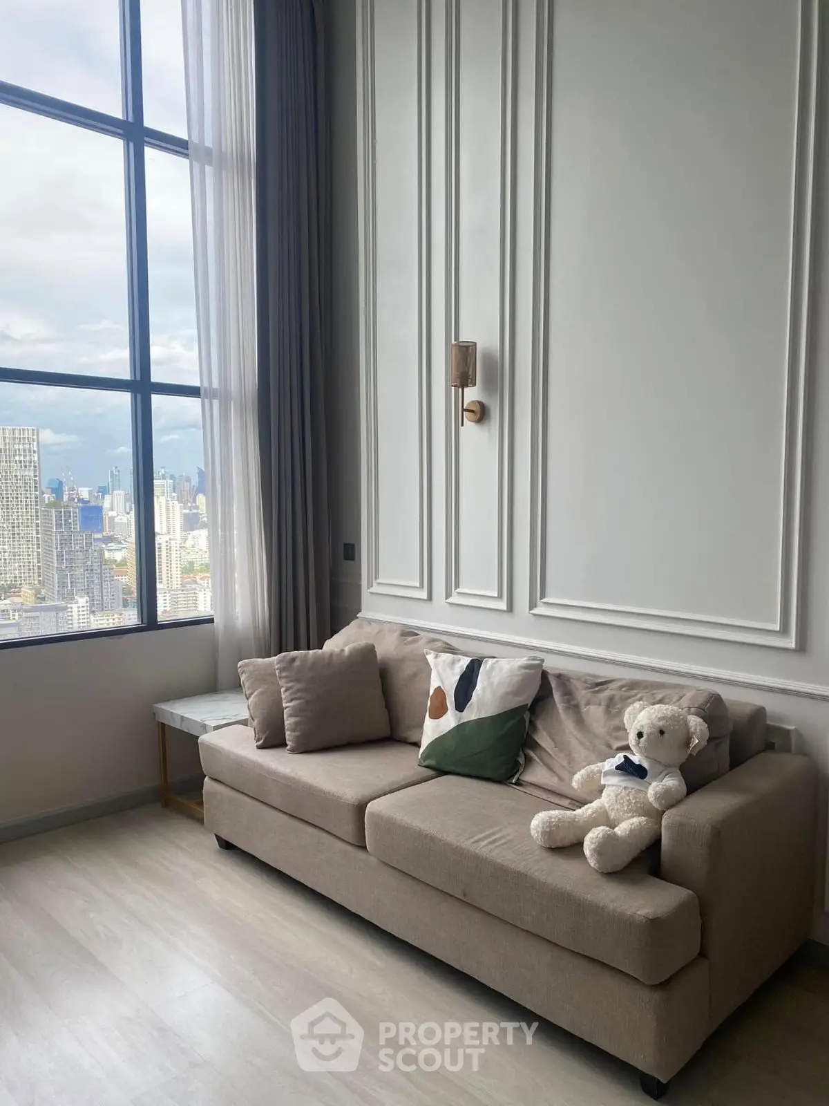 Stylish living room with city view, elegant sofa, and plush teddy bear decor.