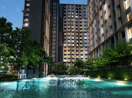 Luxurious condominium with illuminated pool and lush greenery at dusk.