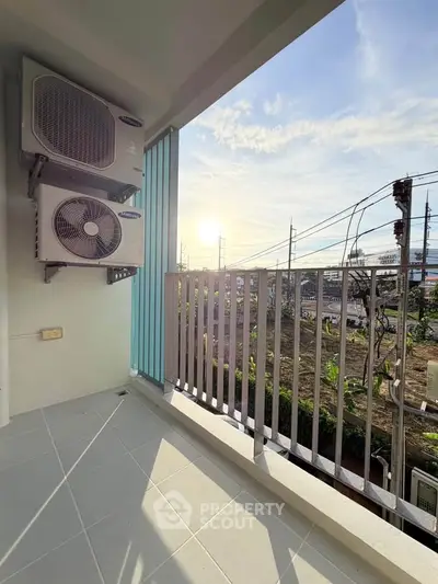 Charming balcony with air conditioning units and scenic sunset view, perfect for relaxation.