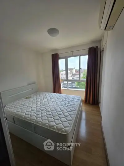 Cozy bedroom with large window and air conditioning, offering a bright and comfortable living space.