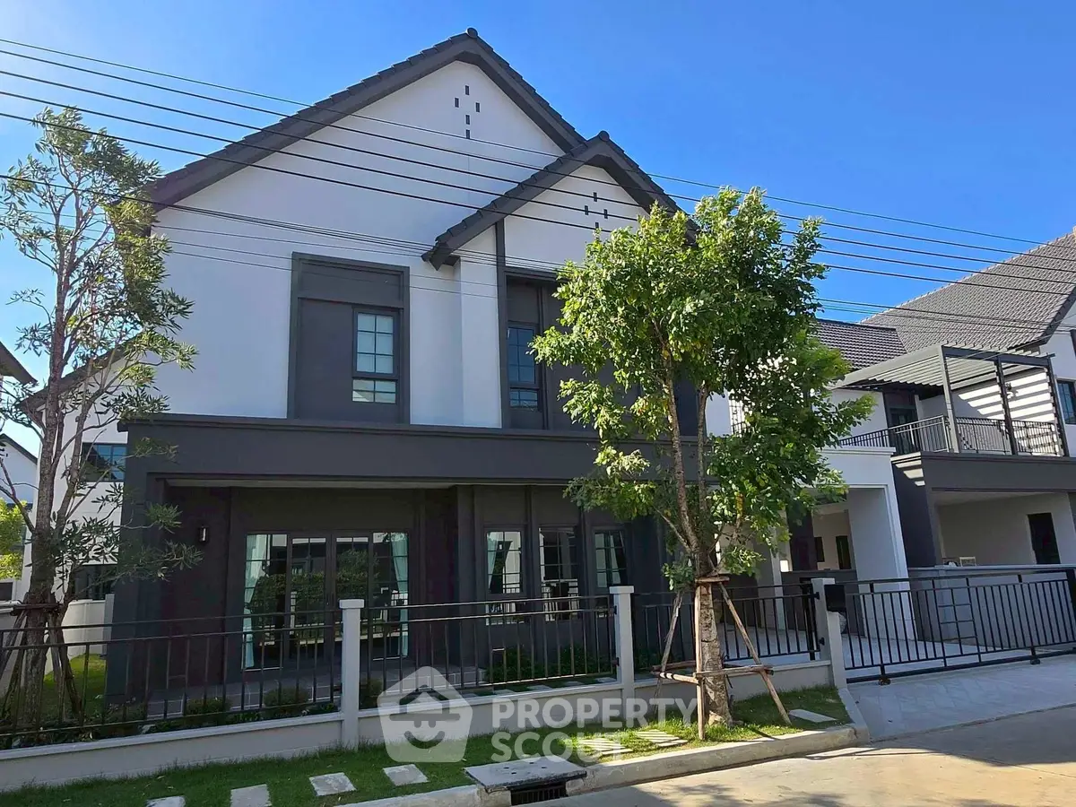 Modern two-story house with sleek design and lush greenery in a serene neighborhood.