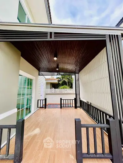 Modern covered patio with wooden flooring and sleek black railings, perfect for outdoor relaxation.